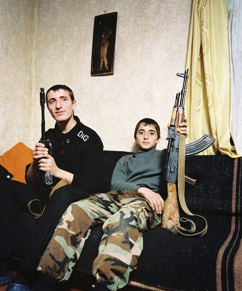 © Rob Hornstra. Courtesy Flatland Gallery. Kuabchara, Abkhazia, 2009 Brothers Zashrikwa (17) and Edrese (14) pose proudly with a Kalashnikov on the sofa in their aunt and uncle’s house. They live in the Kodori Gorge, a remote mountainous region on the border between Abkhazia and Georgia.