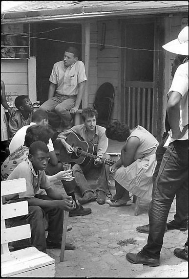 BOB DYLAN BEHIND THE SNCC OFFICE, GREENWOOD, MISSISSIPPI, 1963Gelatin silver enlargement print, 14 x 11 inches (35.6 x 27.9 cm). Printed under the direct supervision of the photographer, 2010. Signed and dated, in pencil, on verso. Photographer's Bleak Beauty stamp on verso. © Danny Lyon / Courtesy Edwynn Houk Gallery Zurich