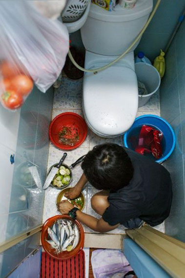 Preparing dinner in the toilet/kitchen –5sqm apartment shared by 2 housemaids in Hong Kong, 2017.from the Series Apples for Sale, 2016-17 © Rebecca Sampson