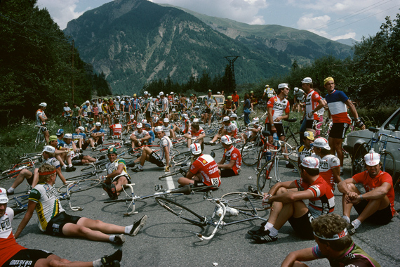 Riders relax whilst the Tour organizers negotiate with farmers on stage 16 to remove their tractors from the road, Tour de France, 1982 © Harry Gruyaert / Magnum Photos