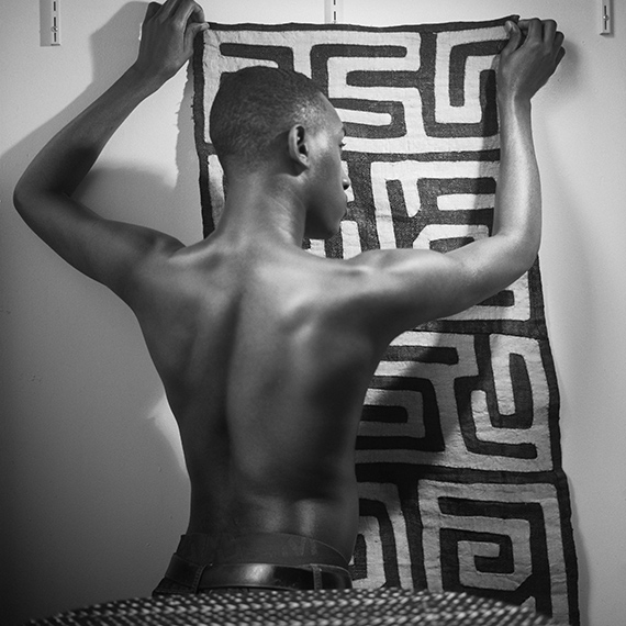 Young man holding up Kuba cloth, 2019 © John Edmonds / courtesy of the artist 