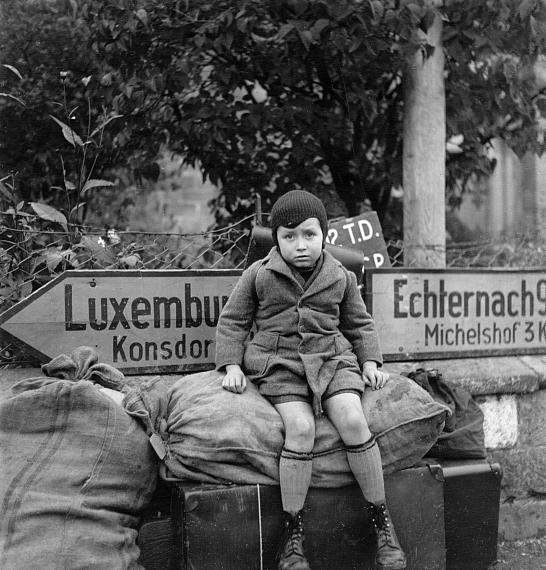 Lee Miller: Small, tired boy waits at crossroads for transport, Iweschtgaass, Bech, Luxembourg, 1945 © Lee Miller Archives England 2022www.leemiller.co.uk