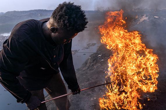 Old Fadama, Accra, Ghana, February 9, 2023. 
Simon Aniah, 24, burns scrap electrical cables to recover copper by the Korle Lagoon. 
© Muntaka Chasant for Fondation Carmignac
