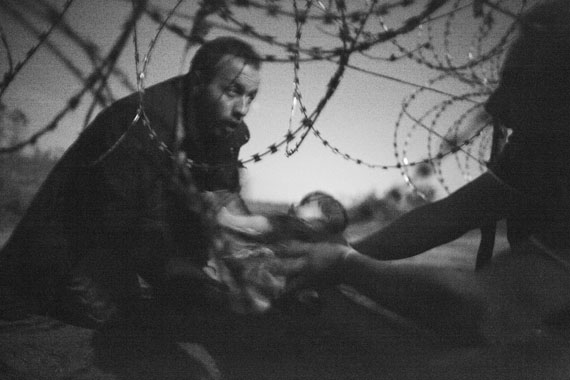 A man passes a baby through the fence at the Hungarian-Serbian border in Röszke, Hungary, 28 August 2015. © Warren Richardson, Australia