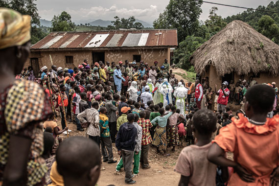 Neighbours and Red Cross burial workers in protective clothing gather outside the home of a family where an 11-month-old girl has died during Congo's Ebola outbreak in the town of Rutshuru in Congo's North Kivu Province, February 2020© Finbarr O’Reilly / Fondation Carmignac