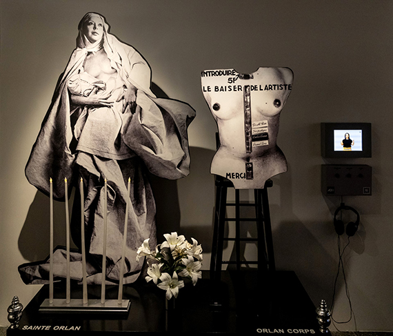 Le Baiser de l’artiste, sculpture et piédestal, 1977
Black and white photographs, wooden base, flowers, candles, 
plastic letters, chair, soundtrack 225.5 x 170 x 70 cm 
© ORLAN